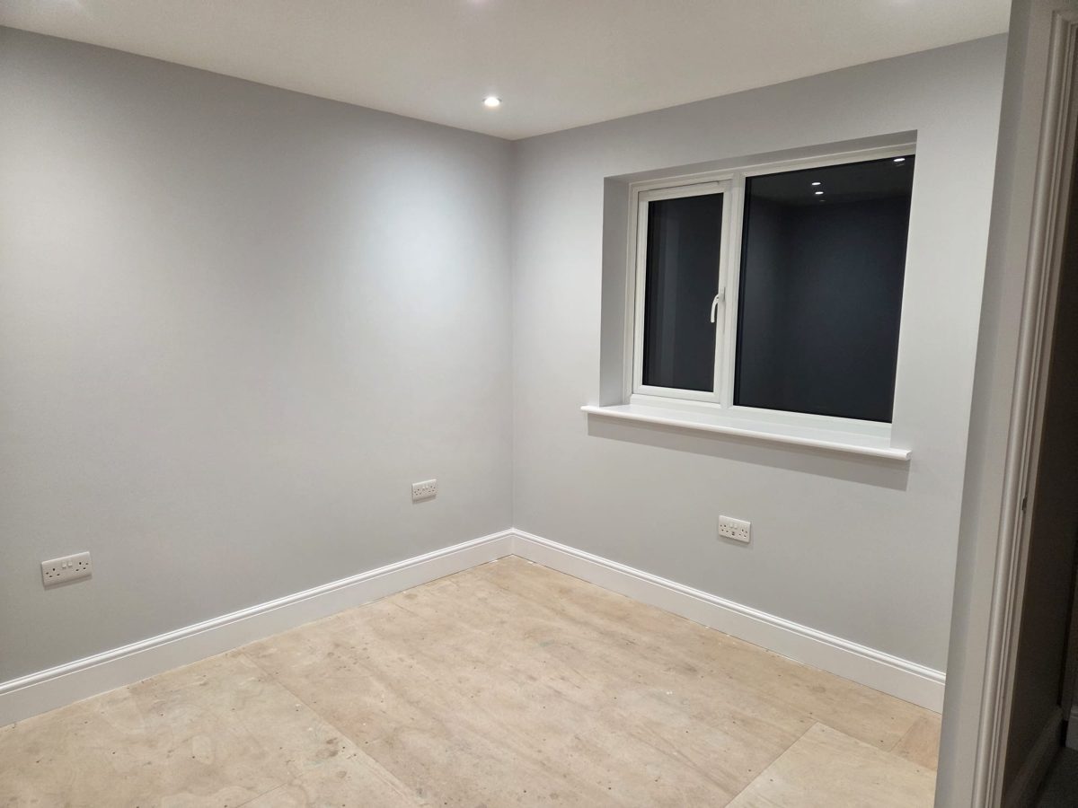 Freshly decorated room with a newly fitted white window, light grey walls and white skirting